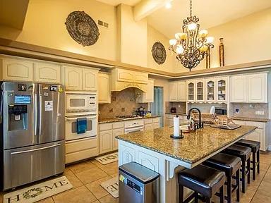 kitchen featuring stainless steel appliances, light tile patterned flooring, a chandelier, backsplash, and beam ceiling