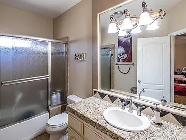 full bath featuring toilet, combined bath / shower with glass door, and vanity