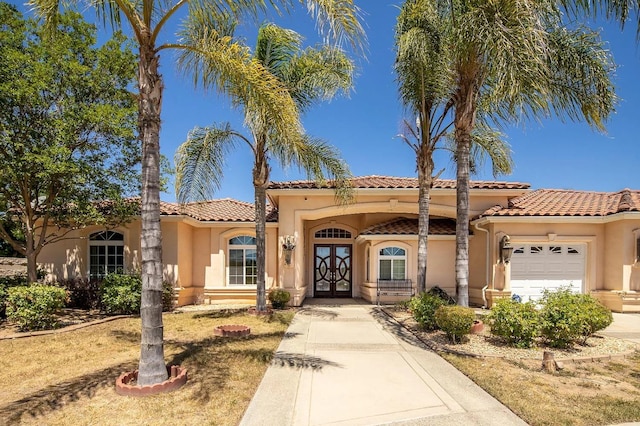 mediterranean / spanish home with french doors, a garage, and stucco siding