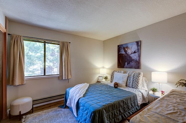 bedroom with wood finished floors, a textured ceiling, and baseboard heating