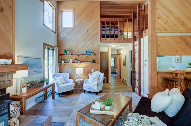 living area with wood walls, plenty of natural light, a high ceiling, and hardwood / wood-style flooring