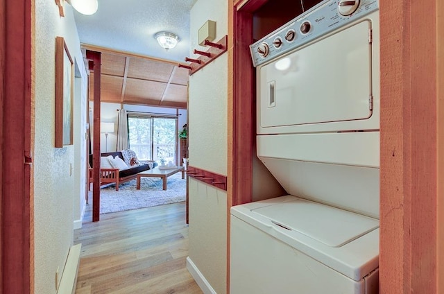 clothes washing area with stacked washer and clothes dryer and light wood finished floors