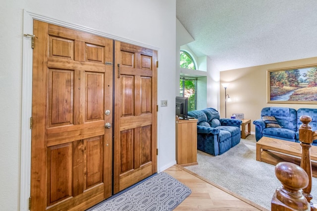 foyer featuring lofted ceiling, a textured ceiling, and baseboards