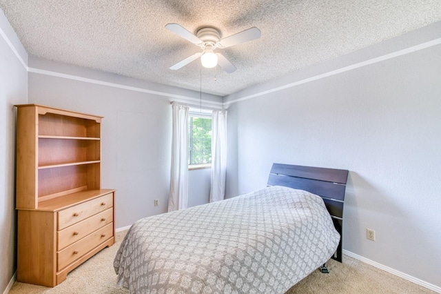 bedroom with light carpet, a textured ceiling, baseboards, and a ceiling fan