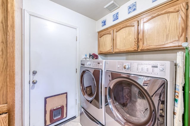 clothes washing area featuring washing machine and clothes dryer and cabinet space