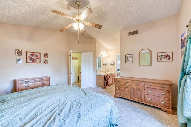 bedroom with light carpet, a textured ceiling, lofted ceiling, ensuite bath, and ceiling fan