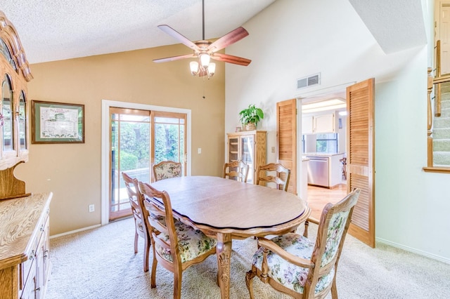 dining area with a ceiling fan, light colored carpet, high vaulted ceiling, a textured ceiling, and baseboards