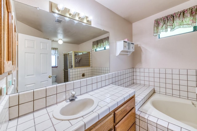 full bathroom featuring healthy amount of natural light, a stall shower, a garden tub, and vanity