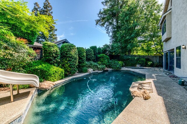 view of pool featuring a water slide, a fenced backyard, and a patio area