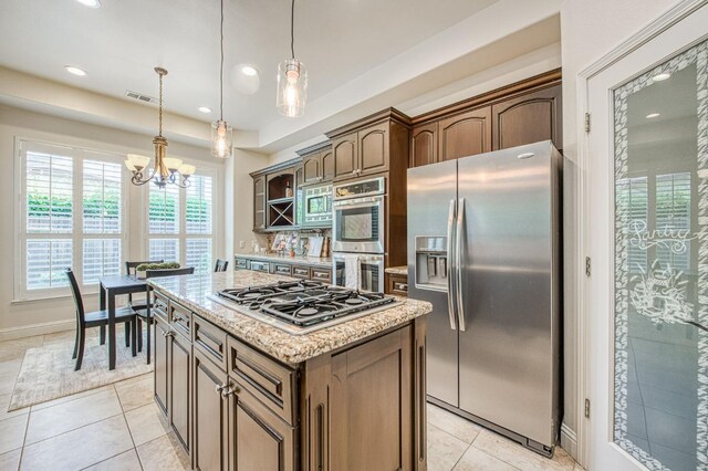 7762 N Hillsdale Dr, Fresno, CA 93720 - kitchen featuring appliances with stainless steel finishes, a kitchen island, light tile patterned floors, a chandelier, and light stone counters