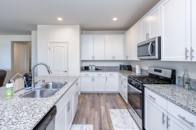 359 Rebel St, Reedley, CA 93654 - kitchen featuring appliances with stainless steel finishes, a sink, white cabinetry, light wood-style flooring, and recessed lighting
