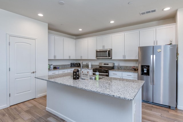 359 Rebel St, Reedley, CA 93654 - kitchen featuring appliances with stainless steel finishes, white cabinetry, light wood-style floors, a kitchen island with sink, and recessed lighting
