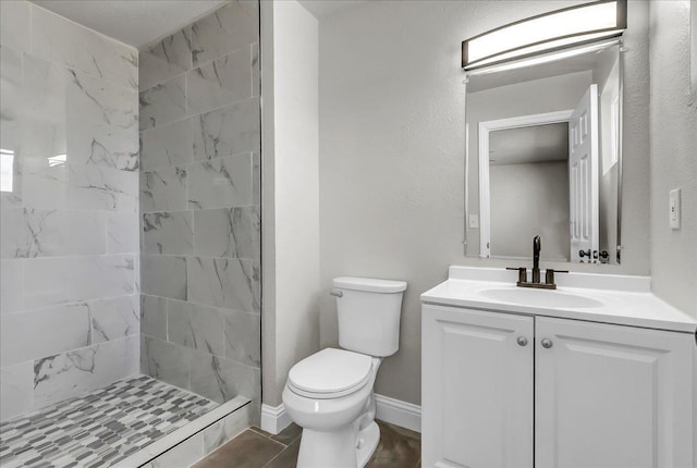 full bath with tiled shower, toilet, vanity, and baseboards