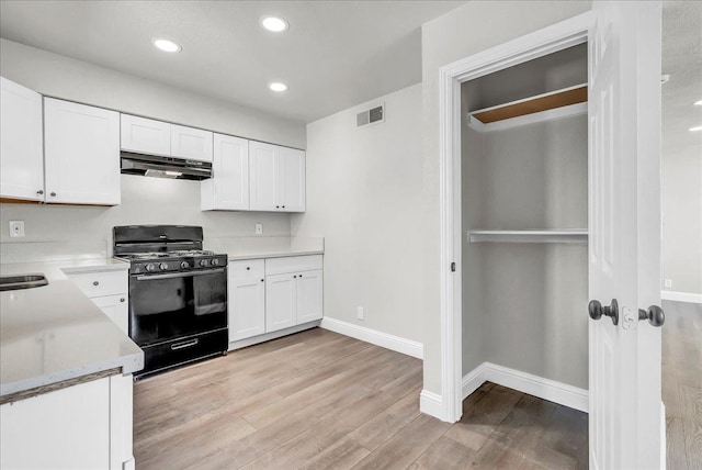 kitchen featuring black gas range, under cabinet range hood, baseboards, light countertops, and recessed lighting