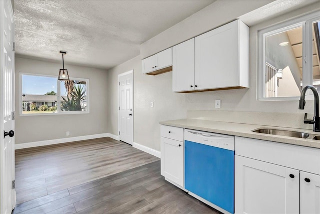 kitchen featuring dishwashing machine, a sink, light countertops, wood finished floors, and a textured ceiling