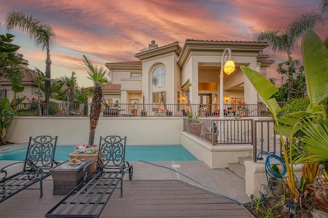 2589 W Lake Van Ness Cir, Fresno, CA 93711 - back of property at dusk featuring stucco siding, a chimney, a tile roof, an outdoor pool, and fence