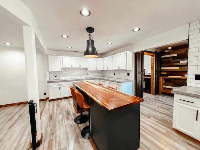 7784 S Del Rey Ave, Del Rey, CA 93616 - kitchen with butcher block countertops, tasteful backsplash, a barn door, white cabinetry, and decorative light fixtures