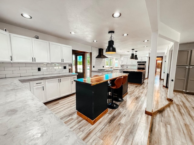 7784 S Del Rey Ave, Del Rey, CA 93616 - kitchen featuring a kitchen island, light wood-style flooring, recessed lighting, backsplash, and white cabinets