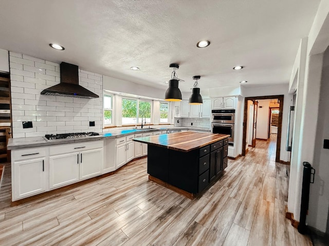 7784 S Del Rey Ave, Del Rey, CA 93616 - kitchen featuring wood counters, appliances with stainless steel finishes, wall chimney exhaust hood, a sink, and white cabinets