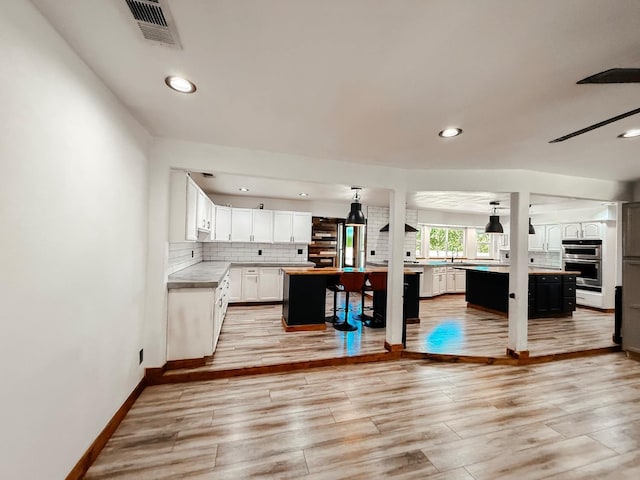 7784 S Del Rey Ave, Del Rey, CA 93616 - kitchen featuring a center island, light countertops, double oven, white cabinetry, and tasteful backsplash