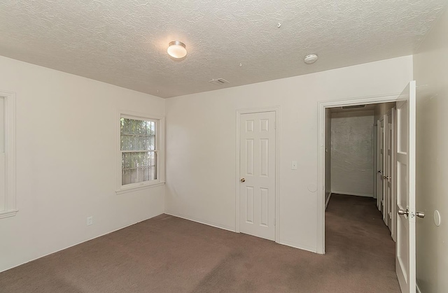 unfurnished bedroom featuring dark colored carpet and a textured ceiling