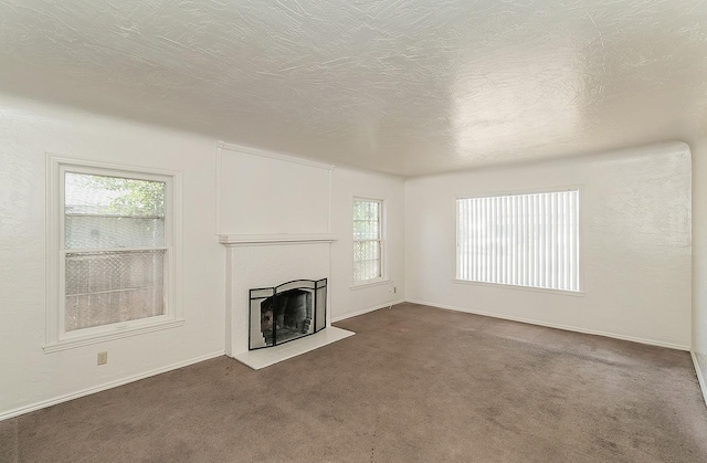 unfurnished living room with a fireplace, dark colored carpet, a textured ceiling, and baseboards