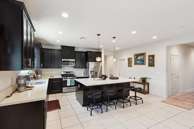 2315 Creekview Dr, Merced, CA 95340 - kitchen with stainless steel appliances, a sink, a breakfast bar, dark cabinets, and light tile patterned flooring