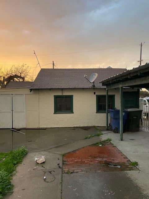 property exterior at dusk with stucco siding and a shingled roof