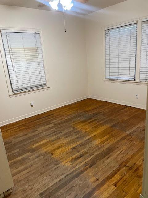 empty room featuring a ceiling fan, hardwood / wood-style flooring, and baseboards