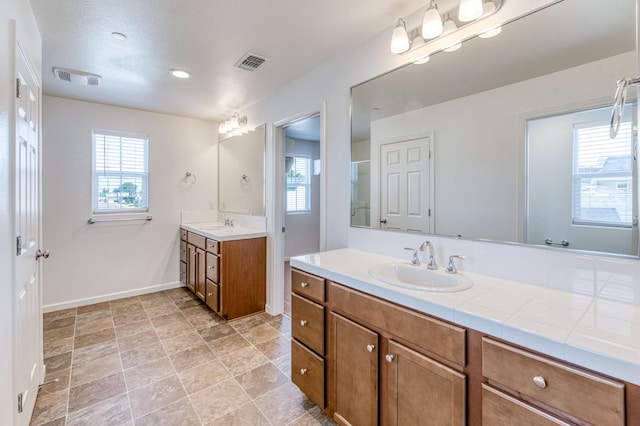 full bathroom with healthy amount of natural light, two vanities, and baseboards