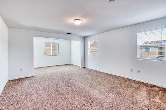spare room featuring carpet floors, healthy amount of natural light, and baseboards