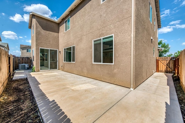 rear view of house featuring a patio, stucco siding, cooling unit, and a fenced backyard