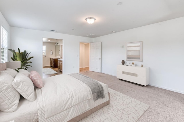 bedroom with light carpet, baseboards, and ensuite bath