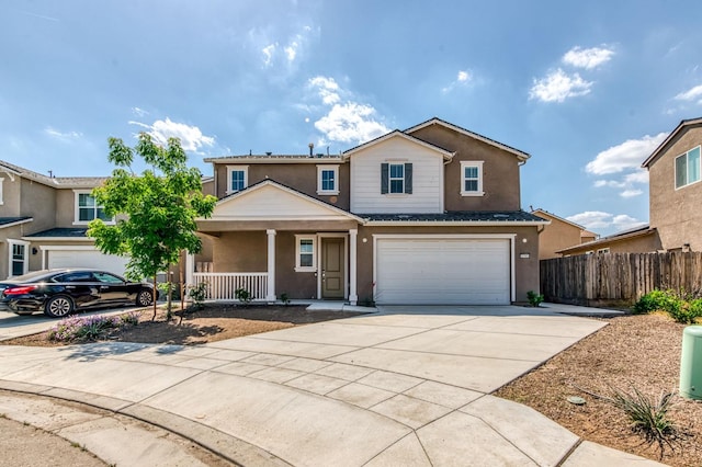 traditional-style house featuring covered porch, fence, driveway, a garage, and stucco siding