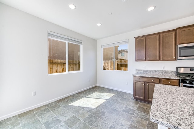 kitchen with stainless steel appliances, baseboards, stone finish floors, recessed lighting, and light stone countertops