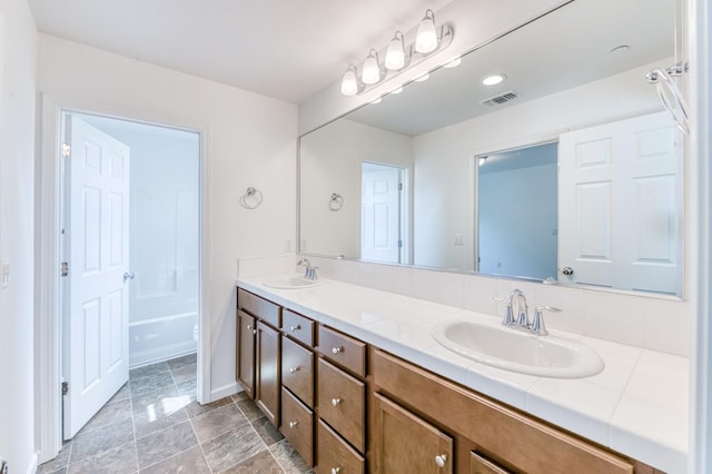 full bathroom with double vanity, stone finish flooring, and baseboards