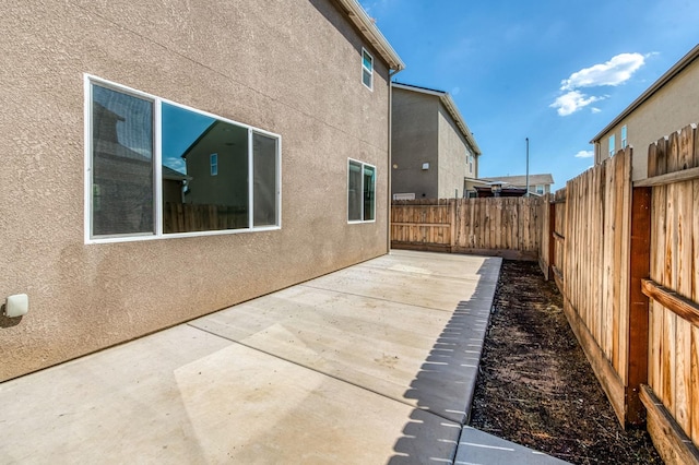 view of side of property with stucco siding, a fenced backyard, and a patio