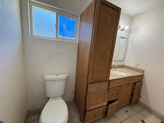 bathroom featuring toilet, vanity, baseboards, and tile patterned floors