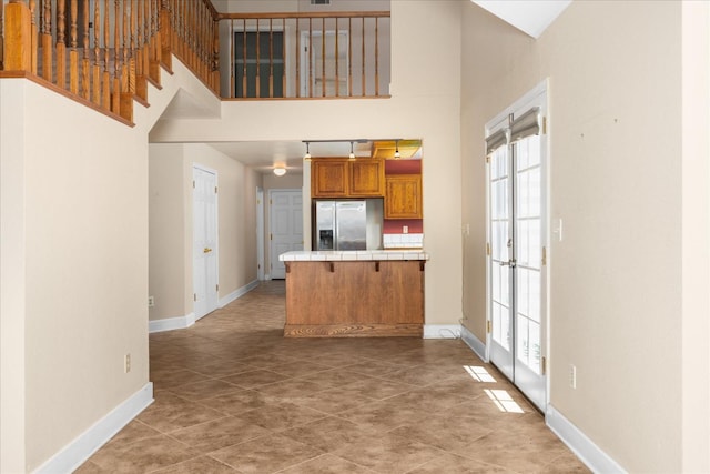 39976 Pierce Lake Dr, Oakhurst, CA 93644 - kitchen with stainless steel refrigerator with ice dispenser, tile countertops, brown cabinetry, baseboards, and a towering ceiling
