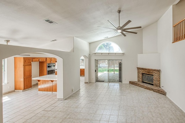 2113 E Portland Ave, Fresno, CA 93720 - unfurnished living room with a ceiling fan, a brick fireplace, arched walkways, high vaulted ceiling, and baseboards