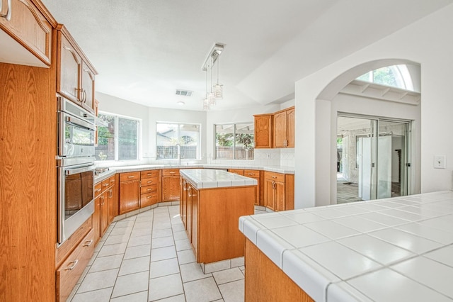 2113 E Portland Ave, Fresno, CA 93720 - kitchen featuring tile countertops, light tile patterned floors, backsplash, a center island, and appliances with stainless steel finishes