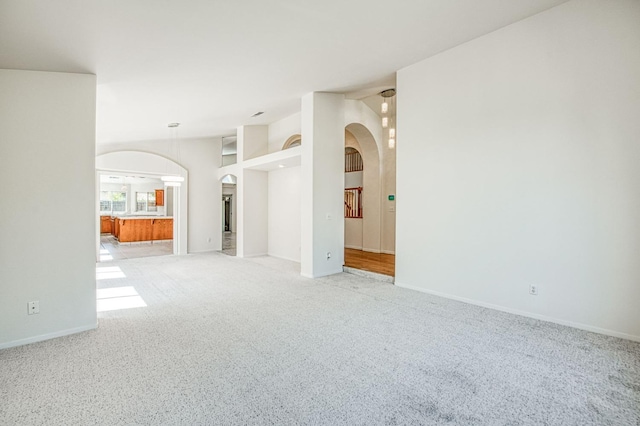 2113 E Portland Ave, Fresno, CA 93720 - unfurnished living room featuring arched walkways, carpet, baseboards, and lofted ceiling