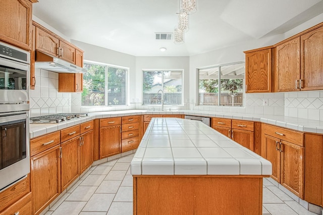 2113 E Portland Ave, Fresno, CA 93720 - kitchen featuring stainless steel appliances, a sink, light tile patterned flooring, tasteful backsplash, and a center island