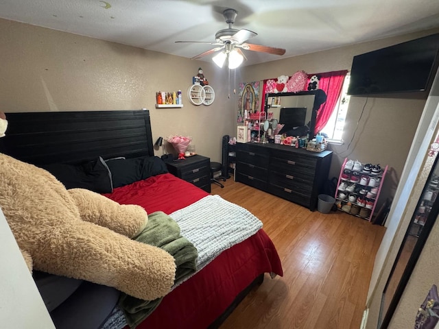 bedroom with wood finished floors, a ceiling fan, and a textured wall