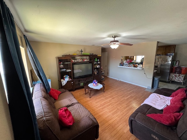 living room featuring ceiling fan, light wood-style floors, and a textured ceiling