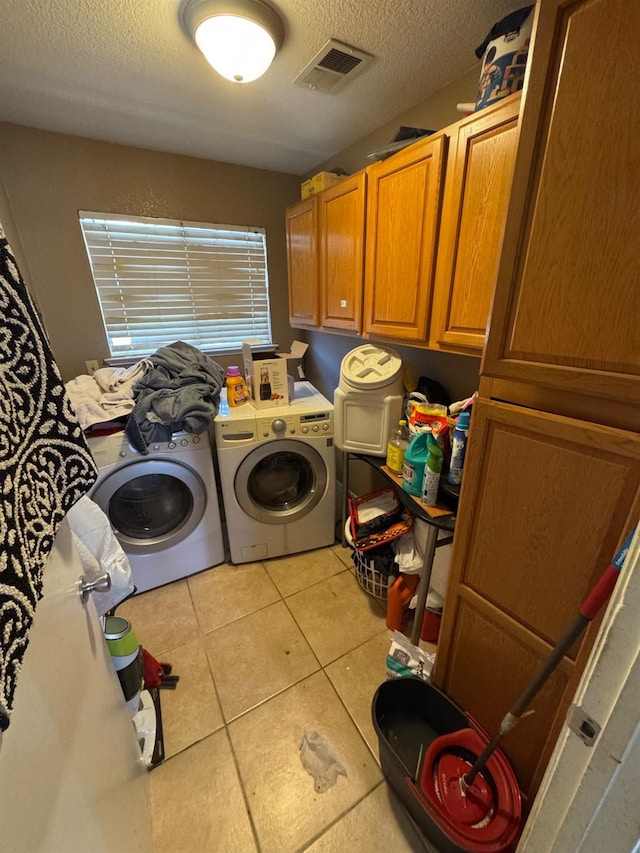 laundry area featuring cabinet space, a textured ceiling, washer and clothes dryer, and tile patterned floors