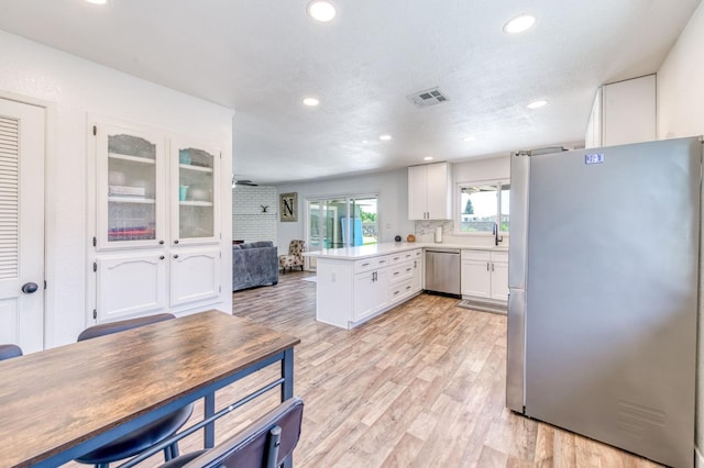 5932 E Illinois Ave, Fresno, CA 93727 - kitchen with appliances with stainless steel finishes, a peninsula, white cabinetry, light wood-style floors, and recessed lighting