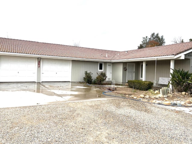 ranch-style home featuring a garage, a tiled roof, and driveway