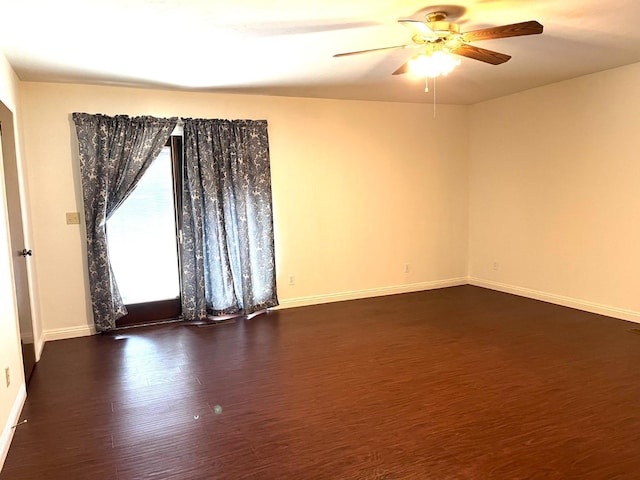 spare room with a ceiling fan, baseboards, and dark wood finished floors