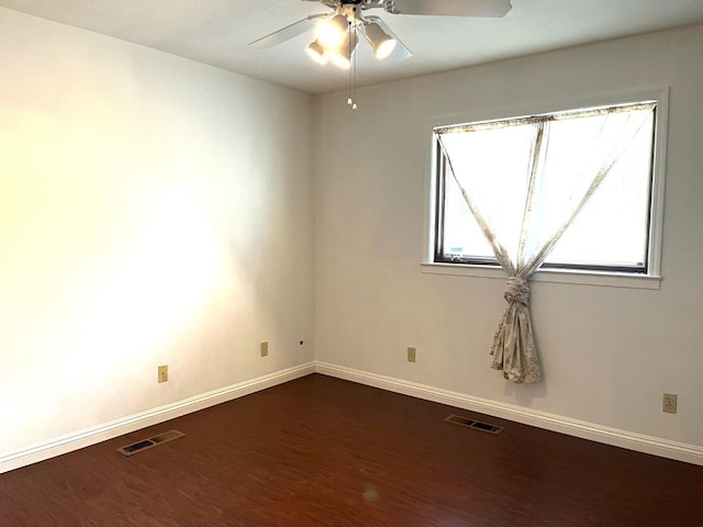empty room featuring dark wood finished floors, a ceiling fan, and baseboards